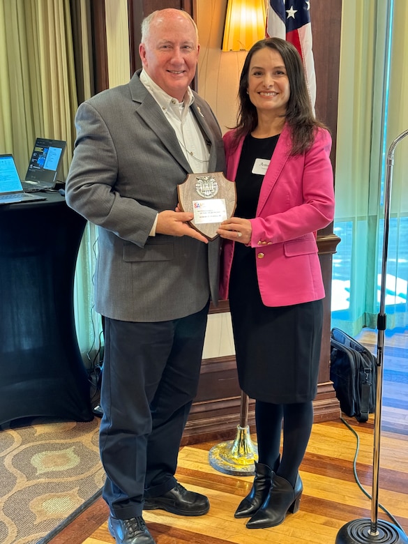 Bob Morris is presented with a plaque for being recognized as the 2023 Distinguished Member of the Year from Ardita Dushi, president of the Society of American Engineers - Fort Worth post.