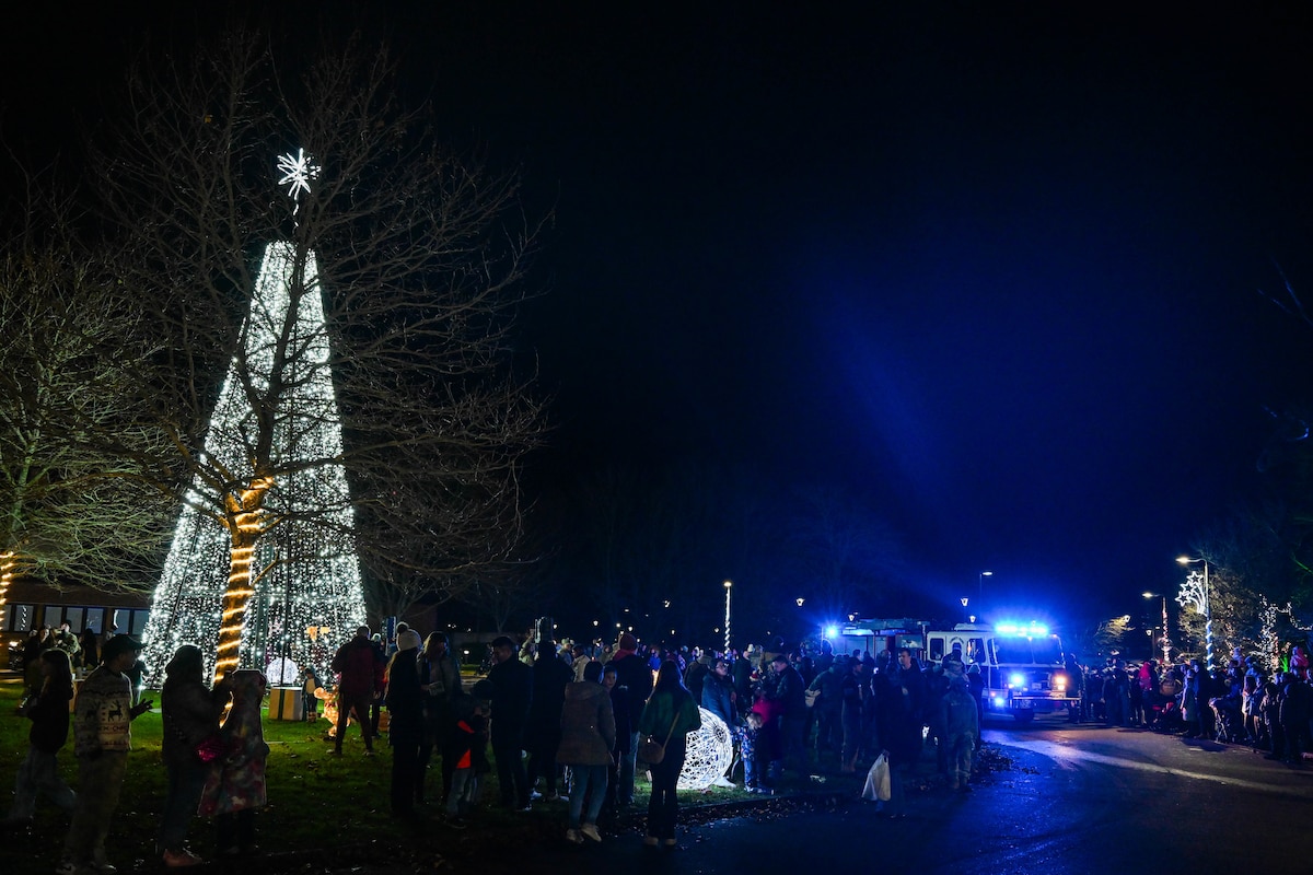 Group of people gather around a lit up tree at RAF Lakenheath.