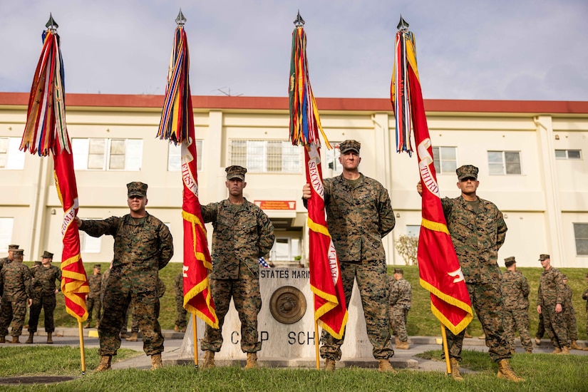 Four Marines stand next to each other holding flags.