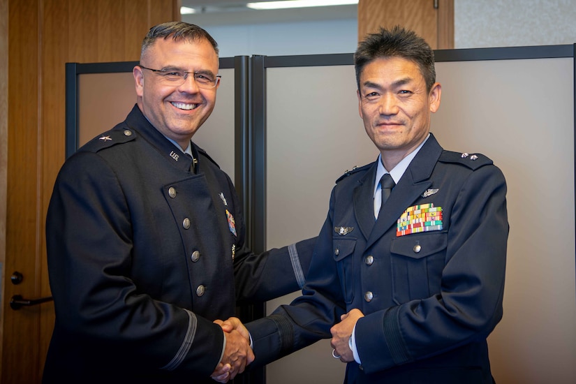 Two military officers shake hands and smile for the camera.