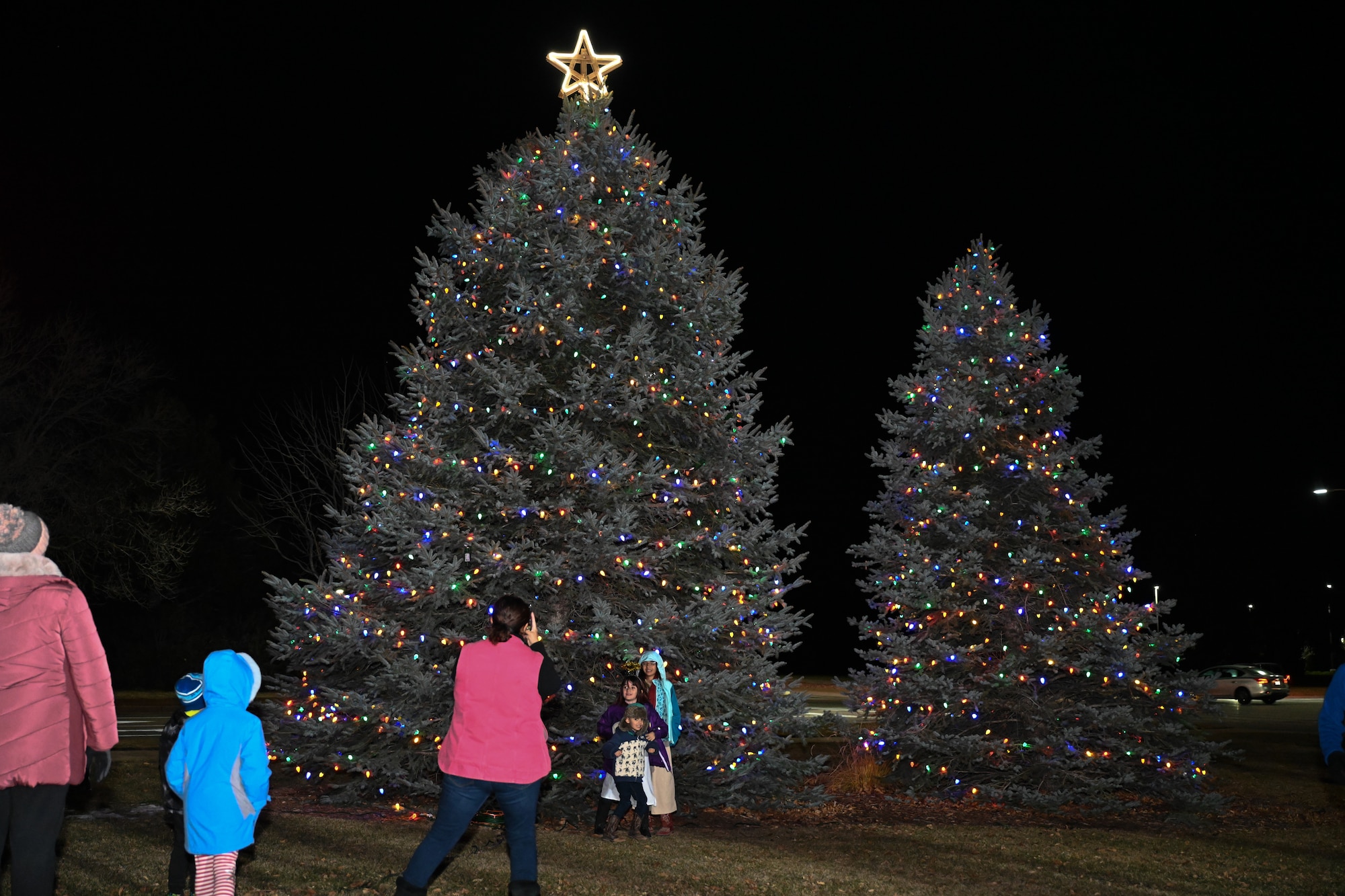 Families pose in front of the Christmas tree to take photos.