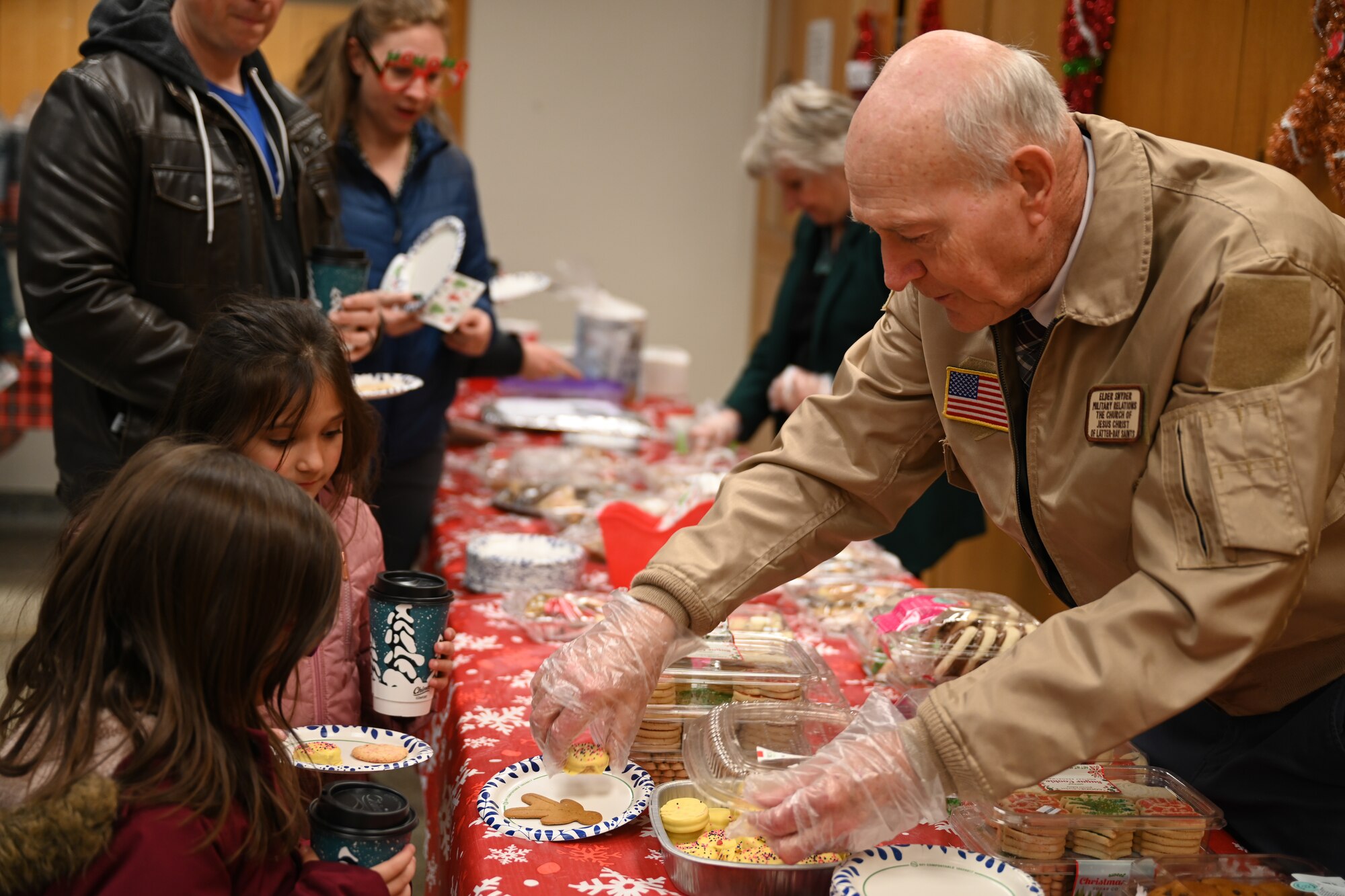 children are receiving cookies from a volunteer during the Christmas tree lighting event.