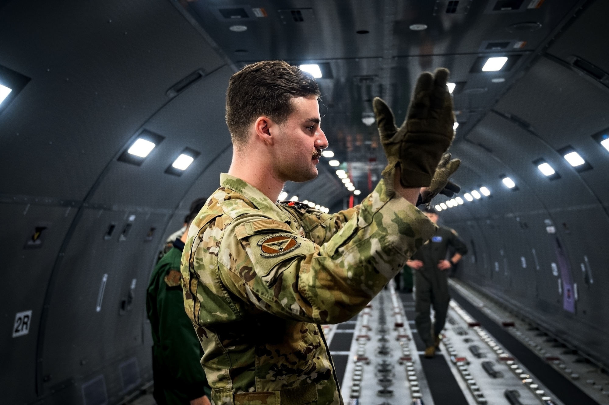 U.S. Air Force Senior Airman Elliott McIntosh, 32nd Air Refueling Squadron boom operator, signals a cargo upload onto a KC-46A aircraft at Joint Base McGuire-Dix-Lakehurst, N.J., Dec. 10, 2024. The JASDF visit involved a subject matter expert exchange designed to enhance interoperability with U.S. Air Force KC-46A aircraft units. (U.S. Air Force photo by Senior Airman Matt Porter)