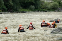 members of the Georgia State Partnership Program wade through a river to train for swift-water recues.