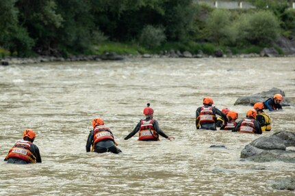 members of the Georgia State Partnership Program wade through a river to train for swift-water recues.