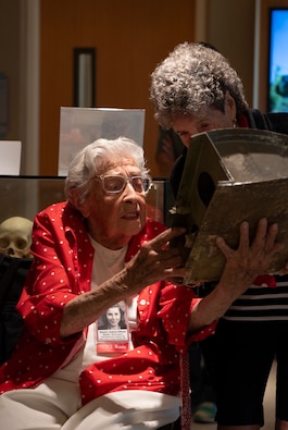 Delphine Klayput (right) and Jeanne Gibson, two Rosie the Riveters, are shown a fragment of aircraft wreckage with the signatures of past Rosies during a tour of the Defense POW/MIA Accounting Agency facility on Joint Base Pearl Harbor-Hickam, Hi., Dec. 9, 2024. Delphine Klayput and Jeanne Gibson, two Rosie the Riveters, toured DPAA's Hawaii lab and were led through the research, recovery and identification elements of DPAA's mission.