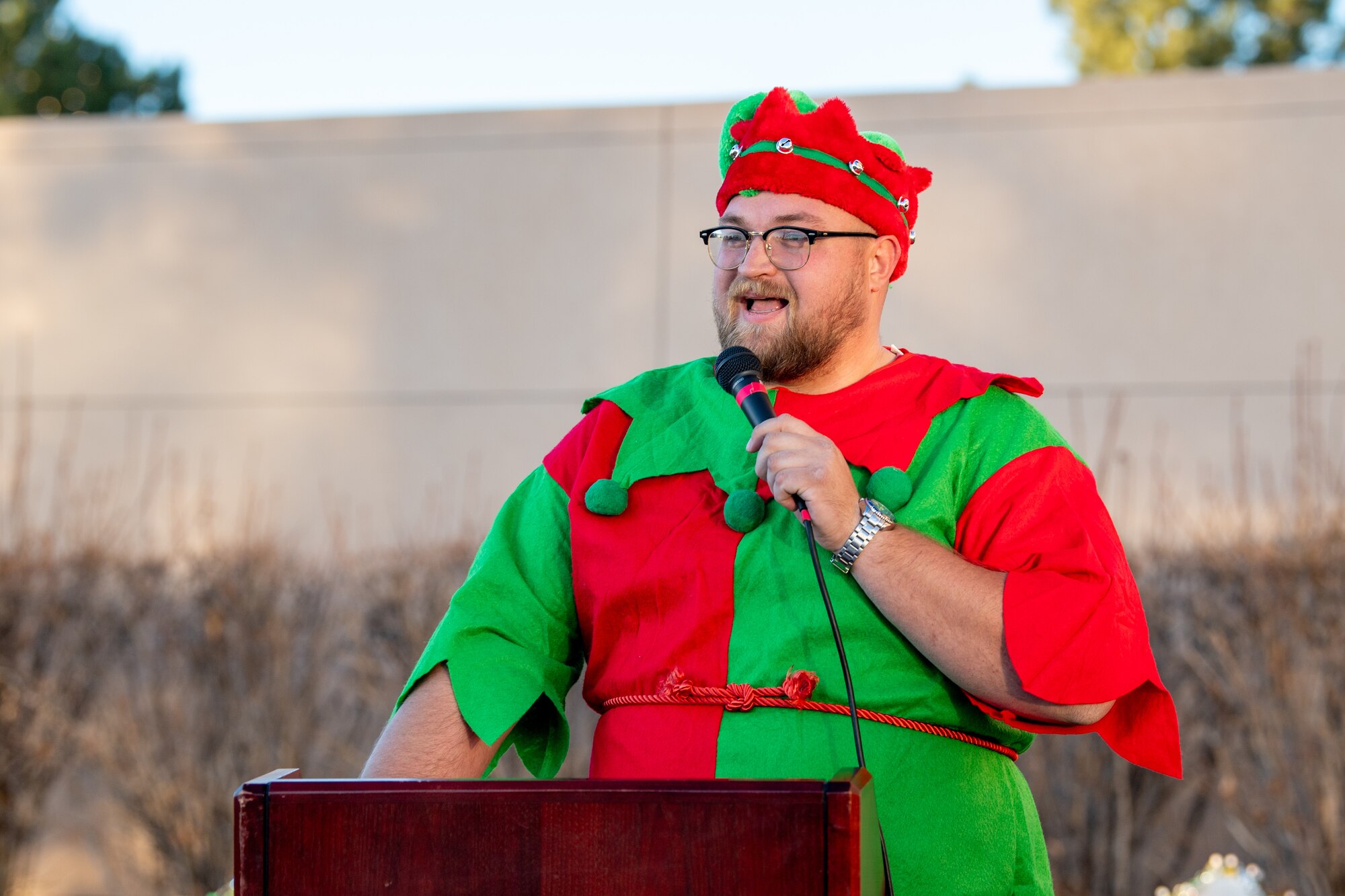 Santa's helper gives remarks while behind a podium.
