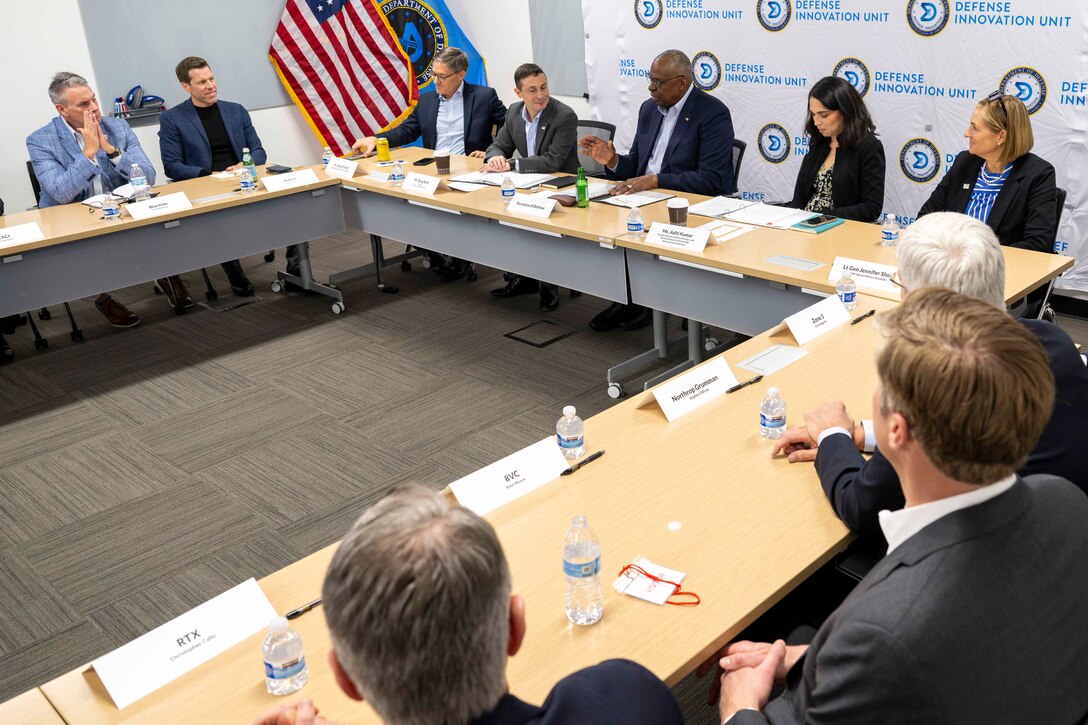 Men and women in civilian attire are seated at tables.