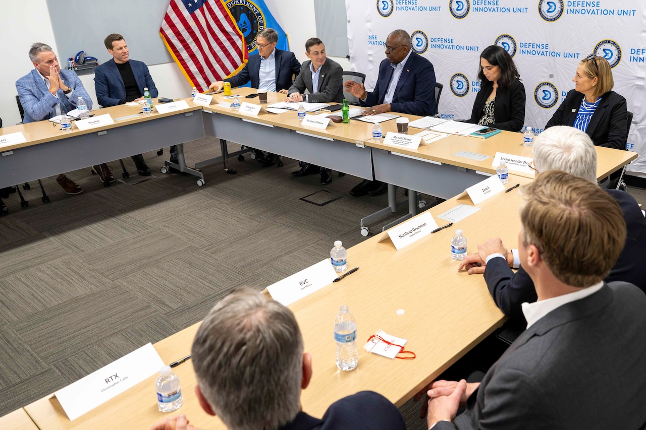Men and women in civilian attire are seated at tables.