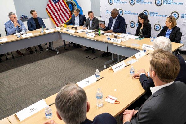 Men and women in civilian attire are seated at tables.