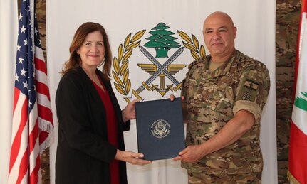 Ambassador to Lebanon Dorothy Shea and Lebanese military official pose in front of flags holding a plaque