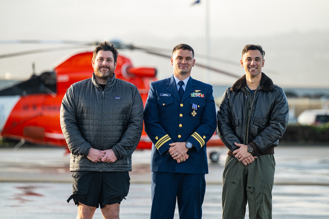 From left, retired Coast Guard aviation survival technician 1st class  Micheal Romano, Lt. Cmdr. Jacob Conrad, Lt. Thomas Smith, pose for a group photo at Coast Guard Air Station San Francisco, Dec. 12, 2024. Romano, Conrad and Smith received recognition for a search and rescue case they conducted, Dec. 30, 2024. (U.S. Coast Guard photo by Petty Officer 3rd Class Hunter Schnabel)