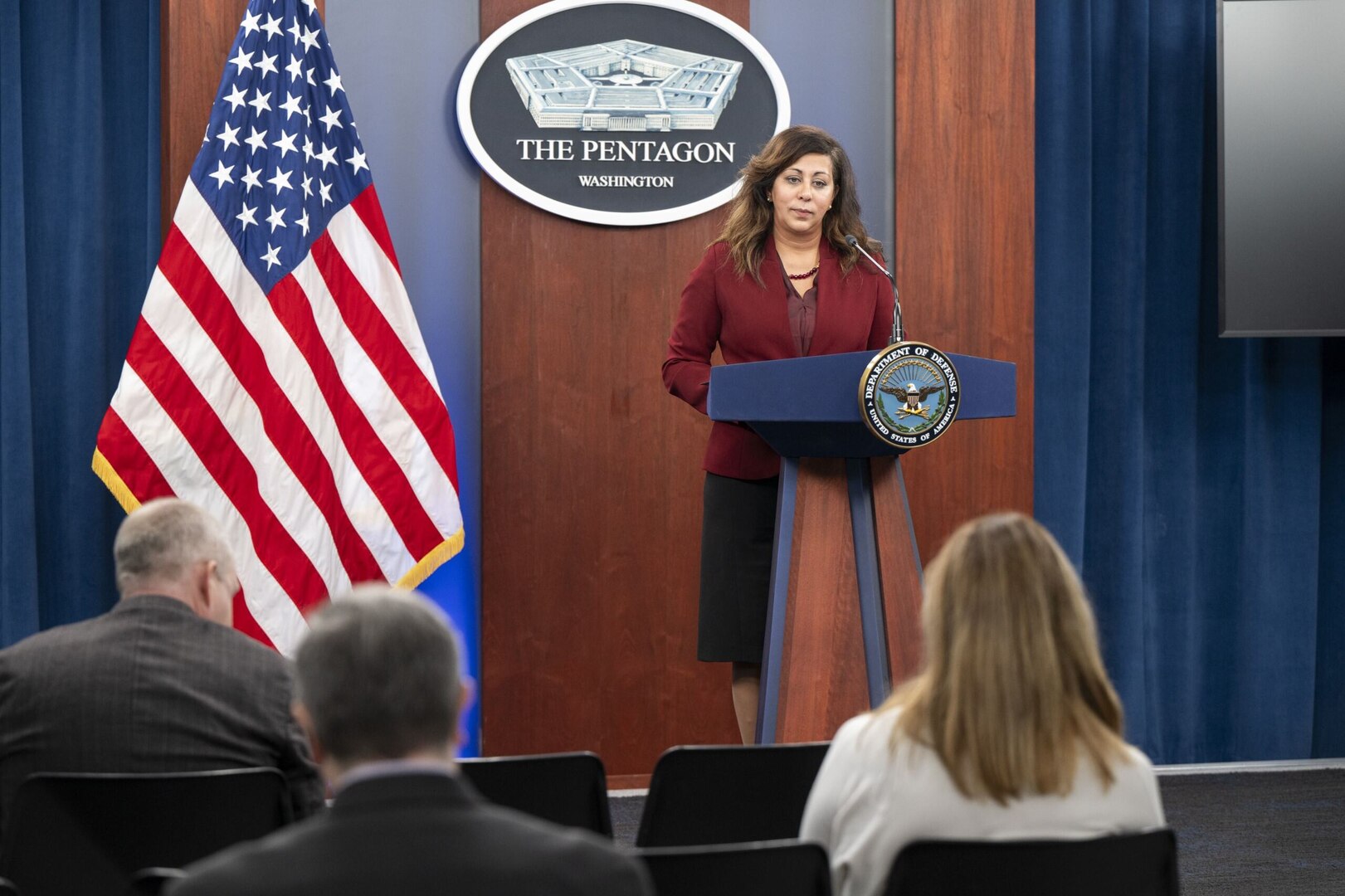 A woman in civilian attire stands at a lectern.