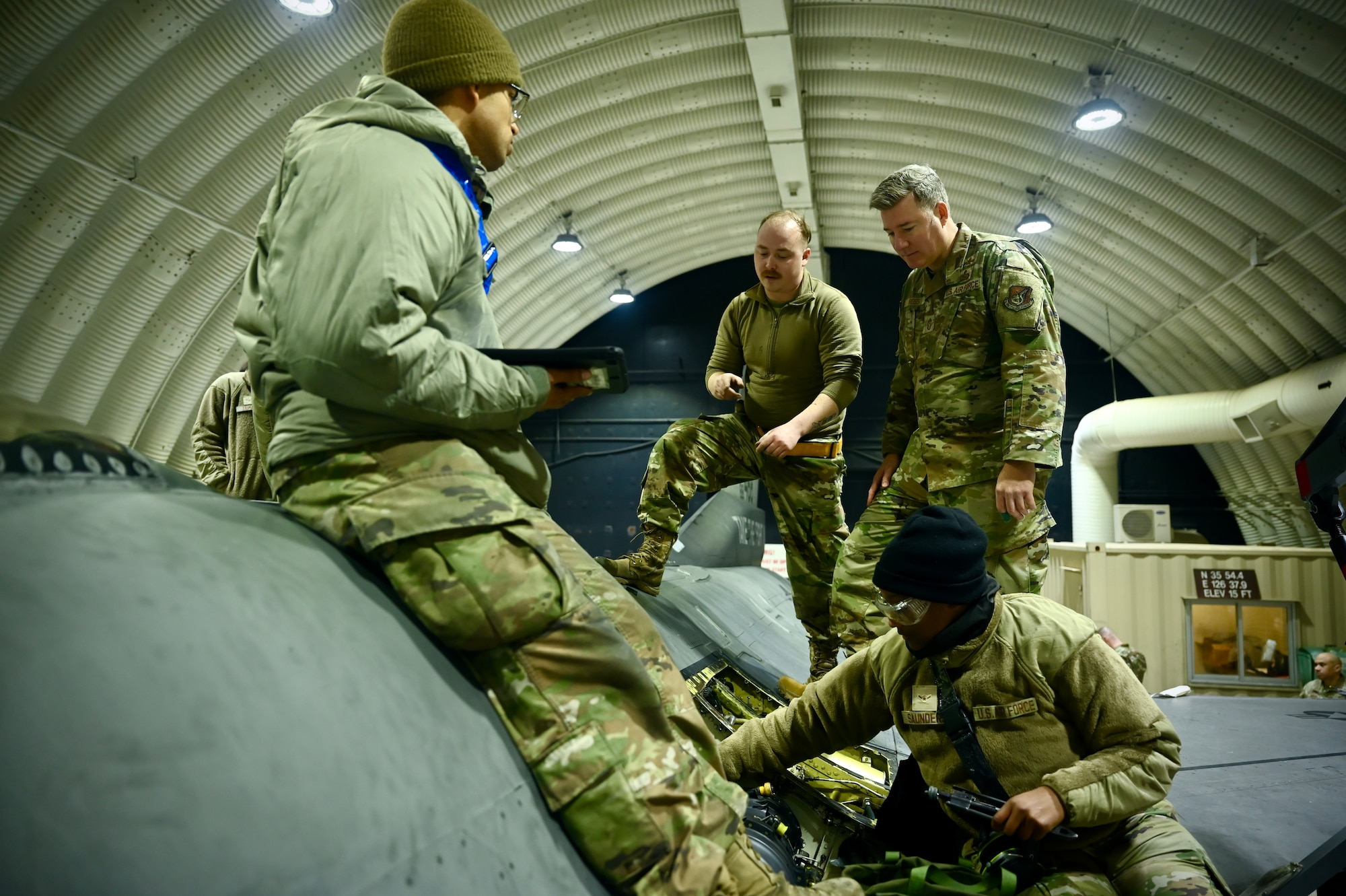 Crew chiefs assigned to the Cobra Fighter Generation Squadron perform routine maintenance on an F-16 Fighting Falcon while Chief Master Sgt. Jeremiah W. Ross, Seventh Air Force command chief, observes during a tour of Kunsan Air Base, Republic of Korea.