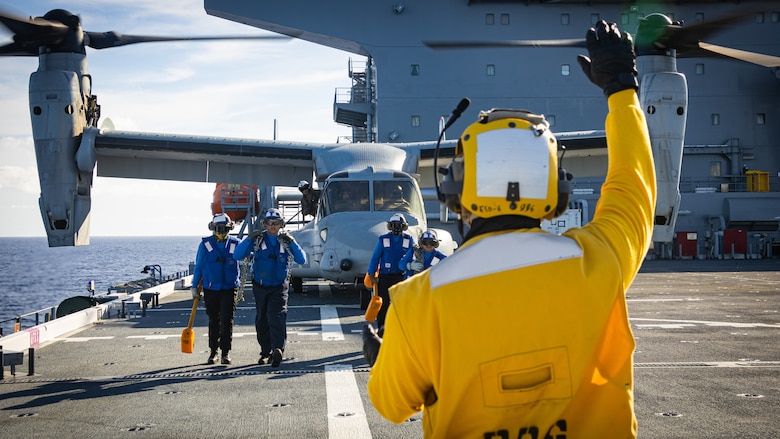 A U.S. Navy Sailor attached to the Expeditionary Sea Base 6 (ESB) USS John L. Canley communicates with hand and arm signals to a U.S. Marine Corps MV-22B Osprey during a deck landing qualification training on the ship as part of exercise Warrior Voyage, off the coast of the island of O'ahu, Hawaii, Oct. 10, 2024. Exercise Warrior Voyage is a group-level training event that evaluates the ESB as an afloat platform for intermediate-level aviation logistics and hot refueling options in support of the Aviation Combat Element. (U.S. Marine Corps photo by Lance Cpl. Moses S. Lopez Franco)