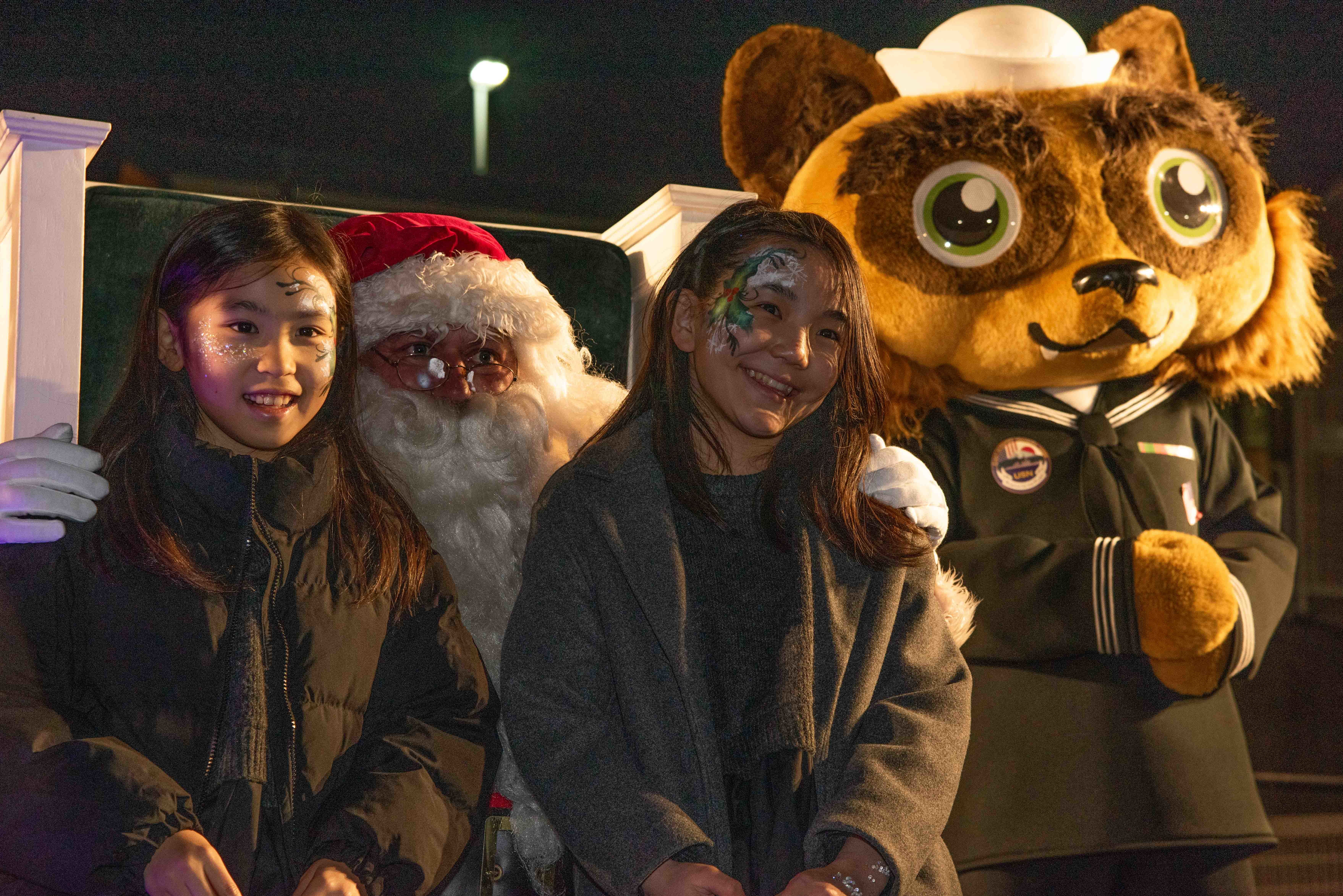 Children at Ikego Heights Housing Area of Commander, Fleet Activities Yokosuka (CFAY), Santa Clause and Yoko-Pon, CFAY’s mascot, pose for a photo during a tree lighting ceremony held at the installation’s joint use field.
