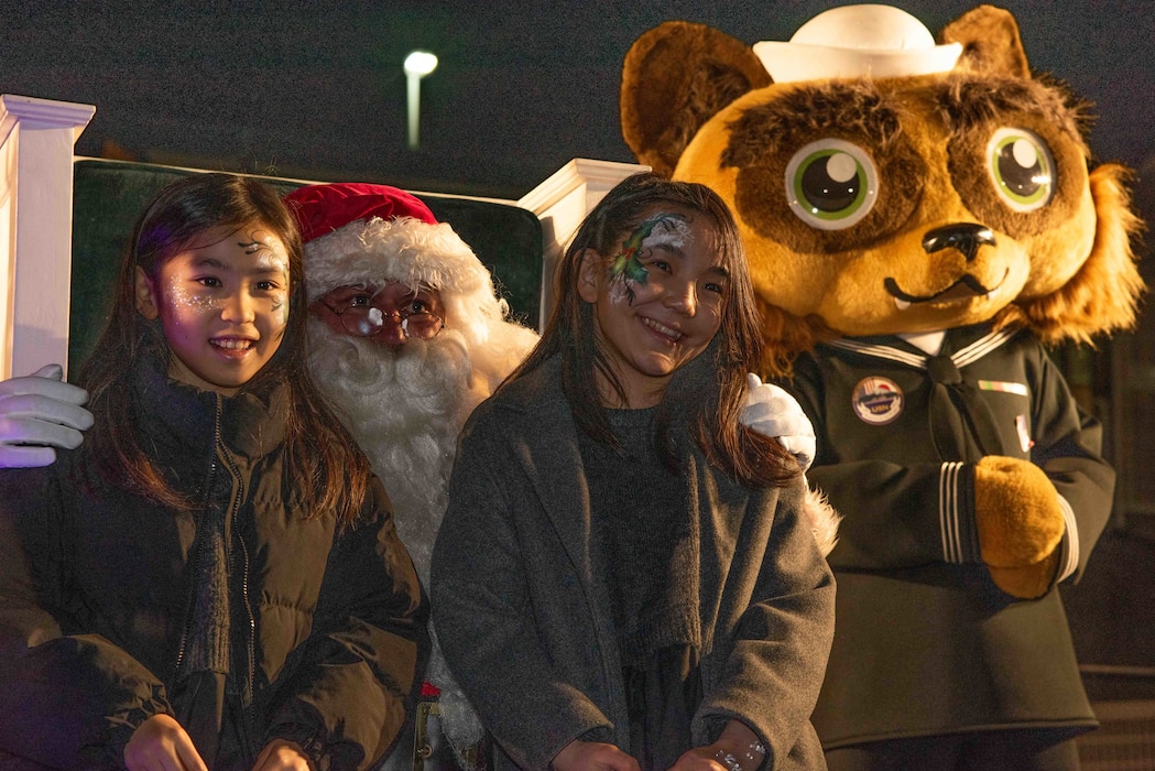 Children at Ikego Heights Housing Area of Commander, Fleet Activities Yokosuka (CFAY), Santa Clause and Yoko-Pon, CFAY’s mascot, pose for a photo during a tree lighting ceremony held at the installation’s joint use field.