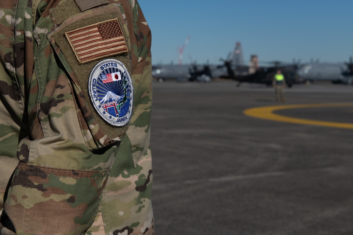 A military member stands at parade rest on the flightline.