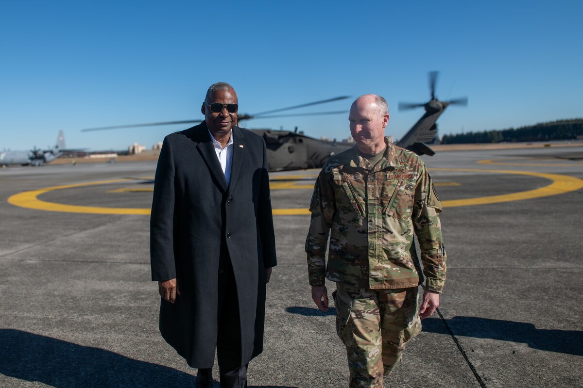 The secretary of defense walks alongside a military member on the flightline.