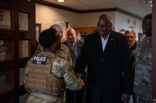The secretary of defense shakes hands with a military member.
