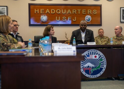 The Secretary of Defense sits at a desk alongside military members.