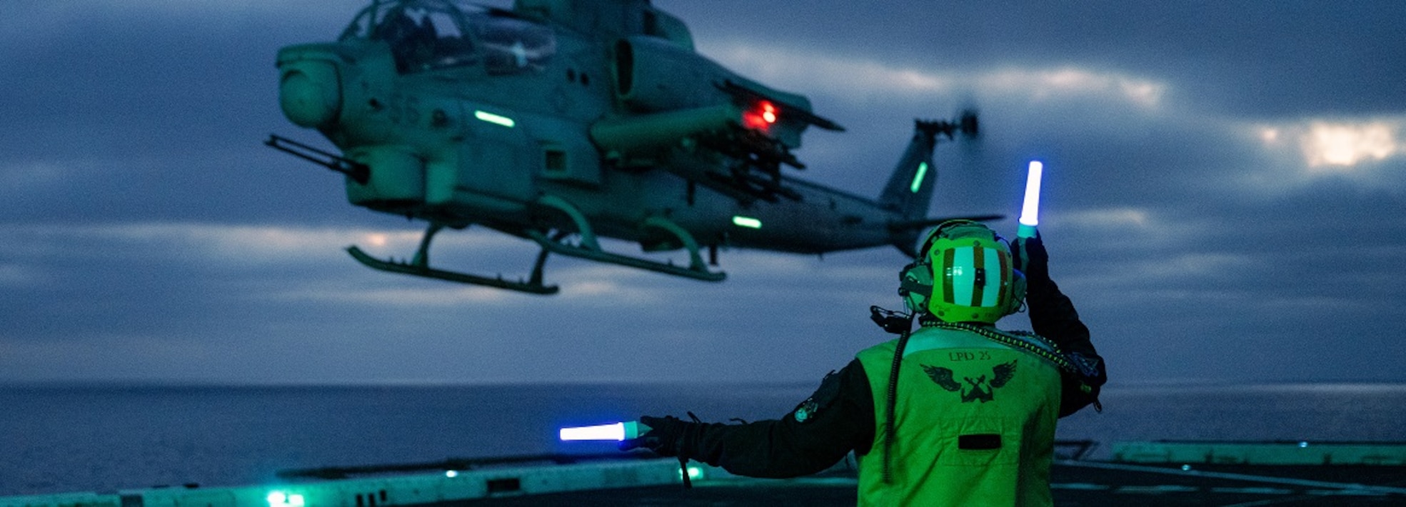 U.S. Navy Aviation Boatswain's Mate (Handling) 1st Class Reyvin Olaes, a native of Cavite, Philippines, signals to a U.S. Marine Corps AH-1Z Viper assigned to Marine Light Attack Helicopter Squadron (HMLA) 169, Marine Aircraft Group 39, 3rd Marine Aircraft Wing, as it takes off from the flight deck of amphibious transport dock ship USS Somerset (LPD 25) during Steel Knight 24 while underway in the Pacific Ocean, Dec. 8, 2024.