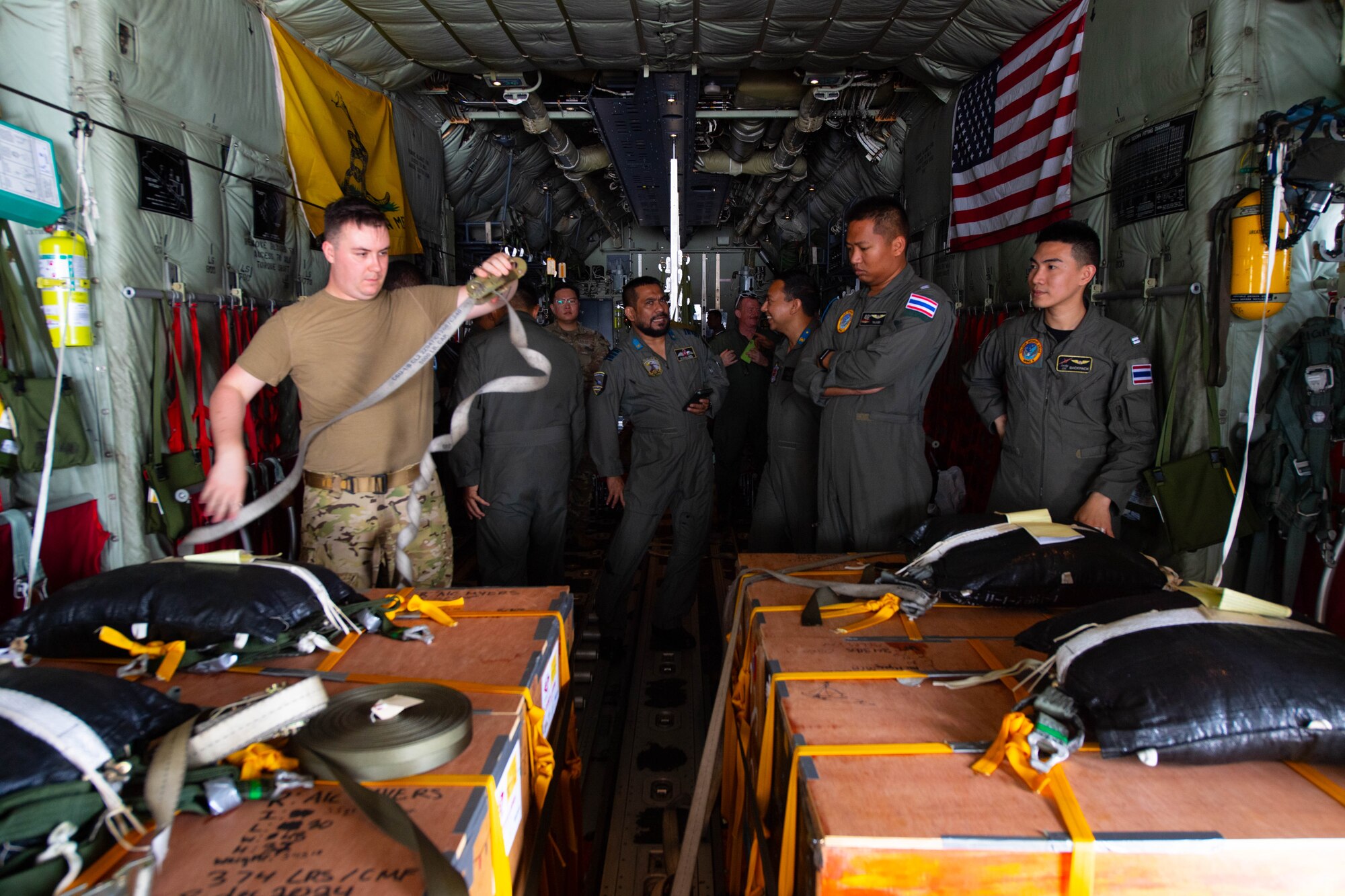 People watch boxes being attached to aircraft.