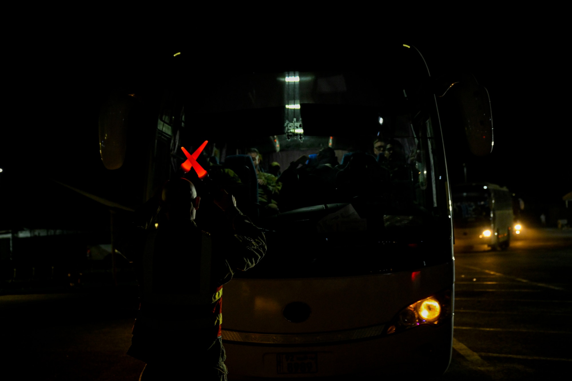 A military member marshals a bus.