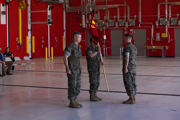 U.S. Marine Corps Maj. Inchul Ha, detachment commander, Combat Logistics Company-34, 3rd Marine Logistics Group, center, holds the company guidon after receiving it from Brig. Gen. Kevin G. Collins, commanding general, 3rd MLG, left, during CLC-34’s activation on Marine Corps Base Camp Blaz, Guam, Dec. 12, 2024. CLC-34’s basing in Guam represents a bolstered dispersal of logistics forces that support III MEF exercises and operations across the Indo-Pacific and are positioned to further enable cooperative security partnerships with regional partners and allies. The activation of CLC-34 marks another step in the planned laydown of Marine forces in the Indo-Pacific region aimed at being geographically distributed and operationally resilient, while maintaining readiness and capability during crises, disasters, or conflicts. (U.S. Marine Corps photo by Cpl. Brayden Daniel)