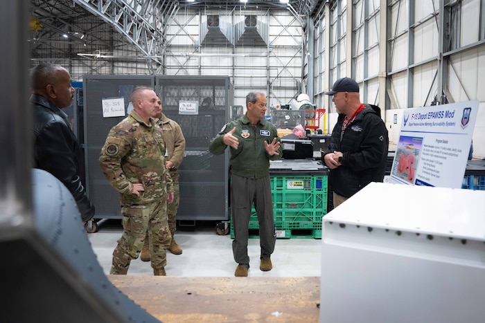 Group of men standing in hangar speaking to one another