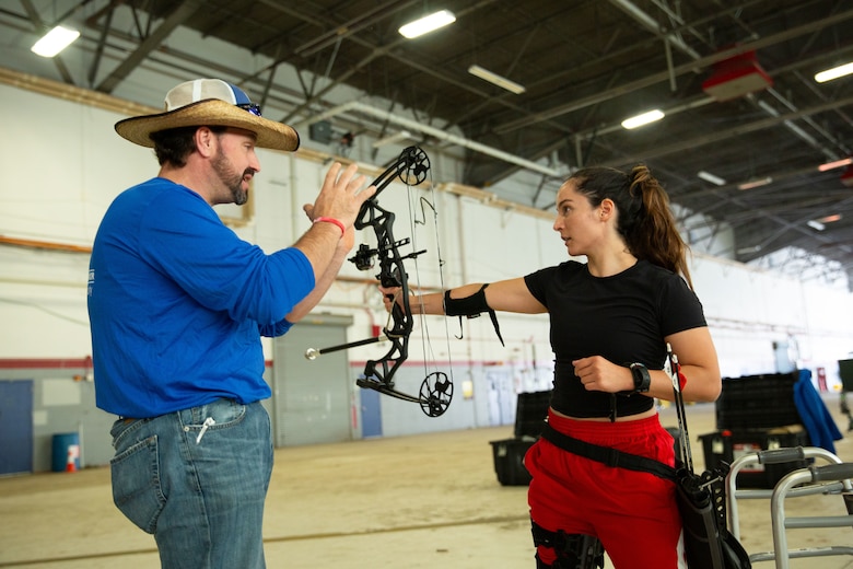 U.S. Marine Corps Gunnery Sgt. Tracey Rodriguez, a recovering service member assigned to Wounded Warrior Battalion - West, receives coaching on shooting a bow and arrow during the 2024 Warrior Care Week at Joint Base Andrews, Maryland, Nov. 20, 2024.