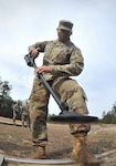 Soldier walks with metal detector outside during training conducted by humanitarian demining training center.