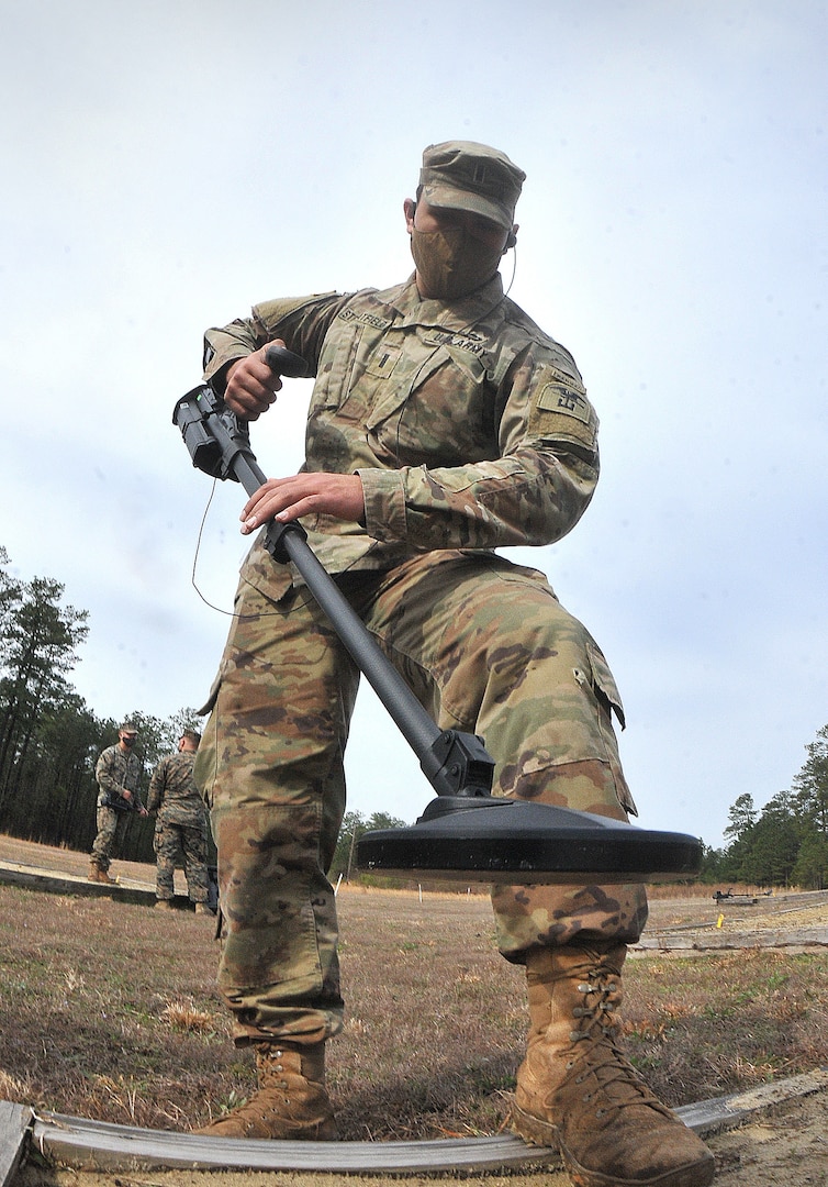 Soldier walks with metal detector outside during training conducted by humanitarian demining training center.