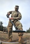 Soldier walks with metal detector outside during training conducted by humanitarian demining training center.