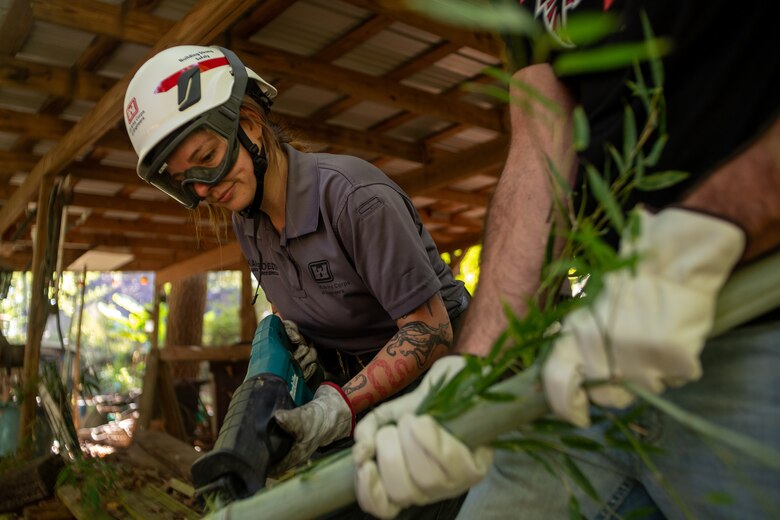 Woman cutting a pipe with a saw.