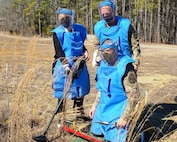 Director Heidi Grant, CMSgt Daniel Simpson, and Col Malcolm Pharr prepare for a landmine clearance drill in deminers Personal Protective Equipment.