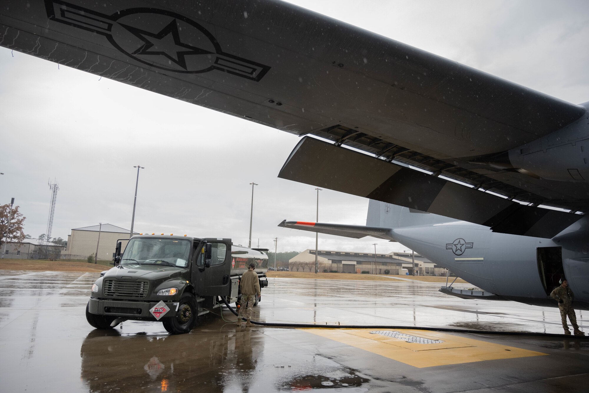 An Airman stands by a fuel trunk wile fueling an aircraft.