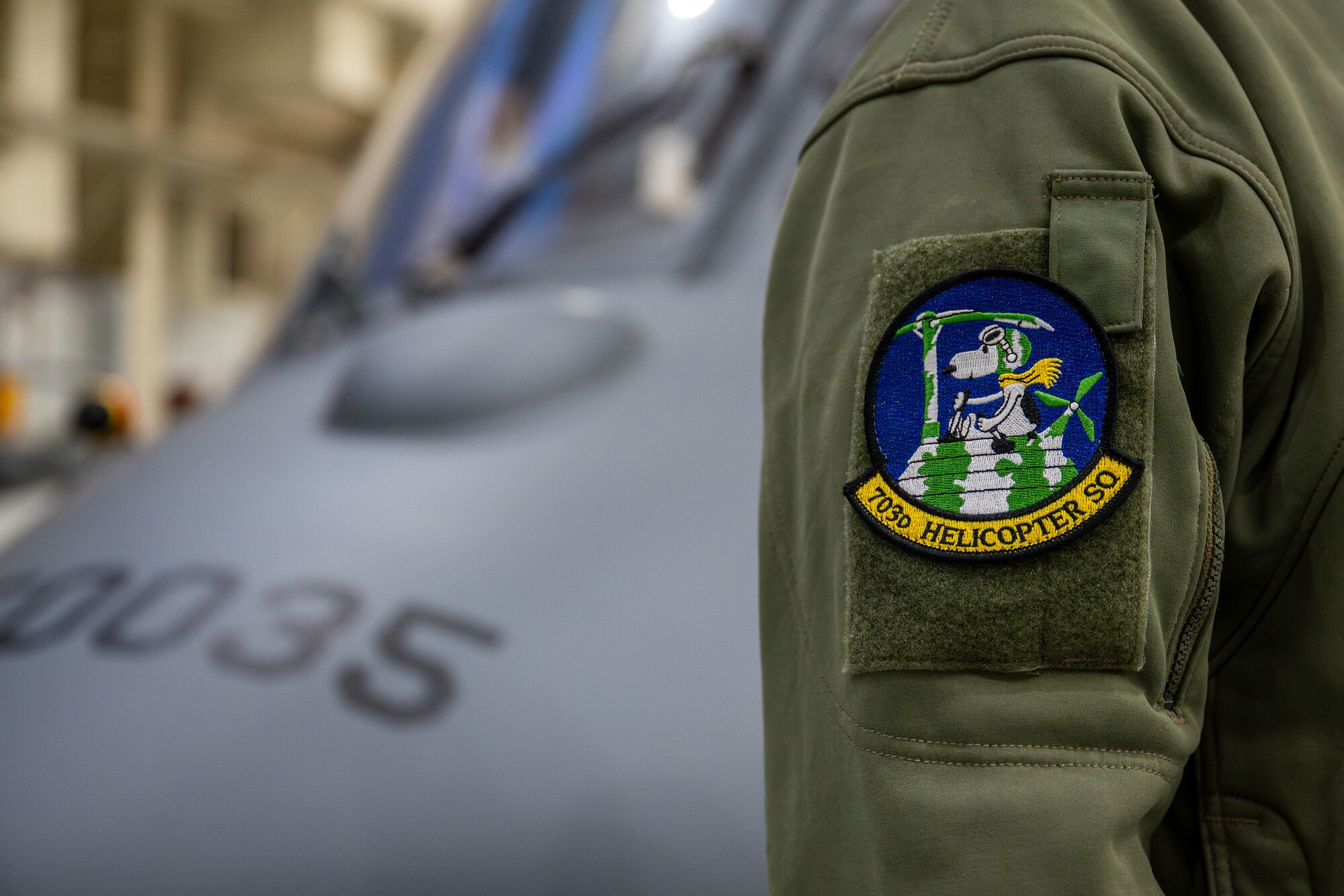 A member from the 703rd Helicopter Squadron displays the unit patch in front of an Integrated Aircrew Systems Trainer at Maxwell Air Force Base, Alabama on Dec. 11, 2024.