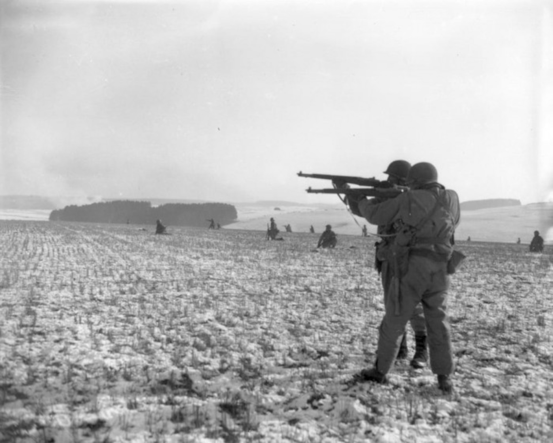 Infantrymen from the 28th Infantry Division with their rifles raised in a farm field near Clervaux, Luxembourg, during the Battle of the Bulge. (U.S. Army photo)