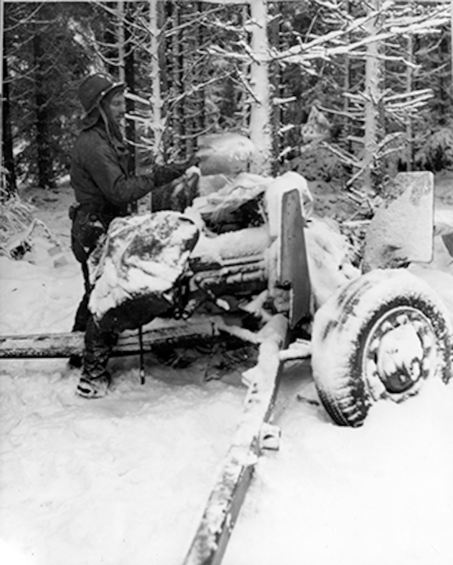 Sgt. William Showers of Benezette, Pennsylvania, cleans the snow from the breech of his 57mm anti-tank gun in the woods near Courtil, Belgium, on January 21, 1945. (U.S. Army photo)