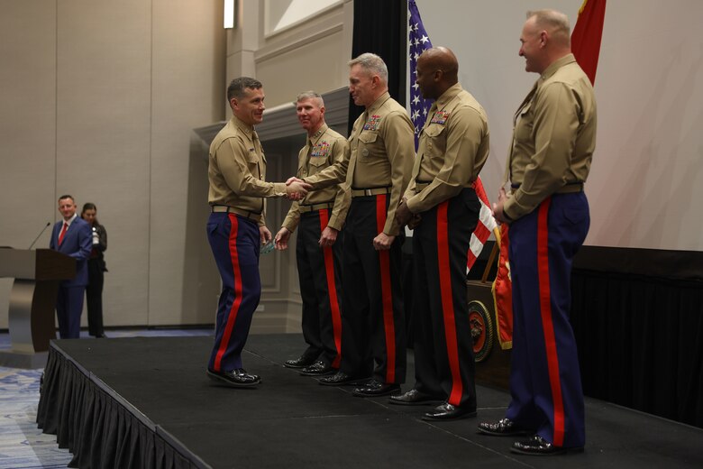 U.S. Marine Corps Capt. Matthew Kreitzer, officer selection officer, Officer Selection Team Spokane, 12th Marine Corps District, left, shakes hands with Maj. Gen. William Bowers, Marine Corps Recruiting Command commanding general, after receiving an award for his achievements throughout Fiscal Year 2024 during the Fiscal Year 2025 National Officer Selection Officer Training Symposium in Orlando on Dec. 11, 2024. NOSOTS is designed to conduct training, discuss recruiting topics and issues and recognize those Officer Selection Teams which have distinguished themselves during the previous fiscal year. (U.S. Marine Corps photo by Lance Cpl. Brenna Ritchie)