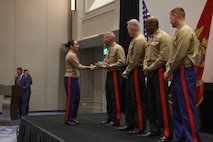 U.S. Marine Corps Capt. Frances Moore, officer selection officer, Officer Selection Team Dallas, 8th Marine Corps District, left, receives an award from U.S. Marine Corps Gen. Eric Smith, 39th Commandant of the Marine Corps, for her achievements throughout Fiscal Year 2024 during the Fiscal Year 2025 National Officer Selection Officer Training Symposium in Orlando on Dec. 11, 2024. NOSOTS is designed to conduct training, discuss recruiting topics and issues and recognize those Officer Selection Teams which have distinguished themselves during the previous fiscal year. (U.S. Marine Corps photo by Lance Cpl. Brenna Ritchie)