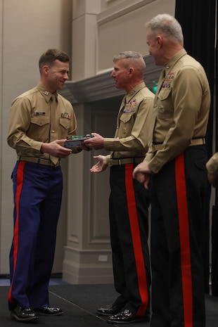 U.S. Marine Corps Capt. Eric Rider, officer selection officer, Officer Selection Station Baton Rouge, 6th Marine Corps District, left, receives an award from U.S. Marine Corps Gen. Eric Smith, 39th Commandant of the Marine Corps, for his achievements throughout Fiscal Year 2024 during the Fiscal Year 2025 National Officer Selection Officer Training Symposium in Orlando on Dec. 11, 2024. NOSOTS is designed to conduct training, discuss recruiting topics and issues and recognize those Officer Selection Teams which have distinguished themselves during the previous fiscal year. (U.S. Marine Corps photo by Lance Cpl. Brenna Ritchie)