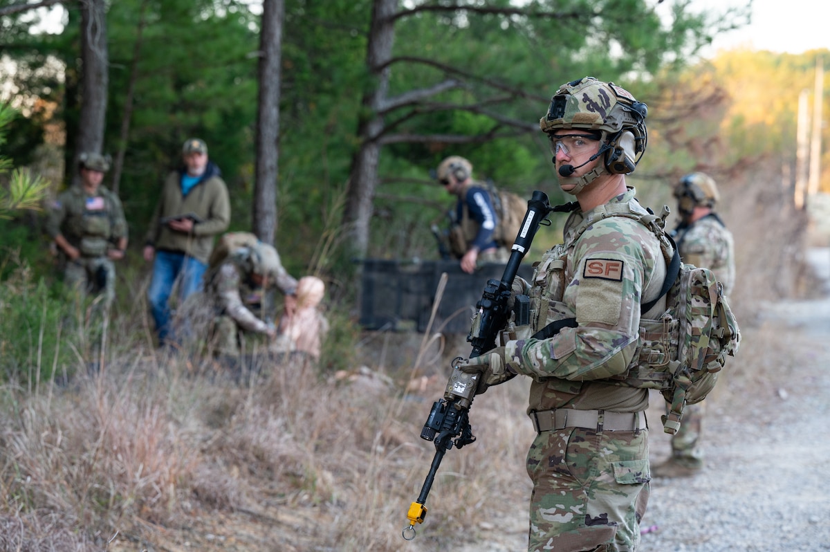An Air National Guard Airman maintains security while U.S. Army Green Berets treat a simulated IED blast victim in the background.