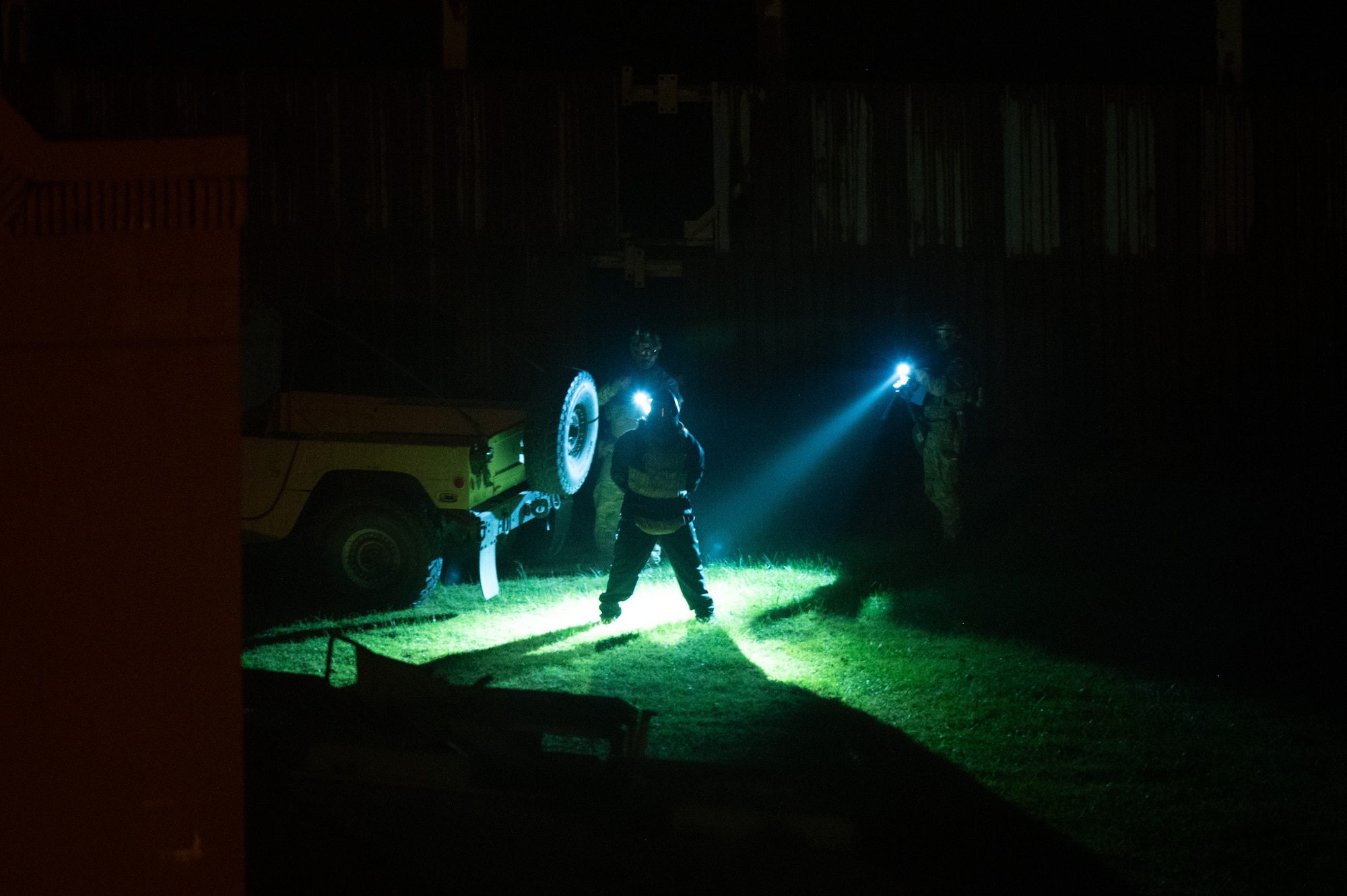 U.S. Air Force security forces personnel assigned to the Air National Guard shine flashlights on and detain an individual acting as a simulated opposing force at night.