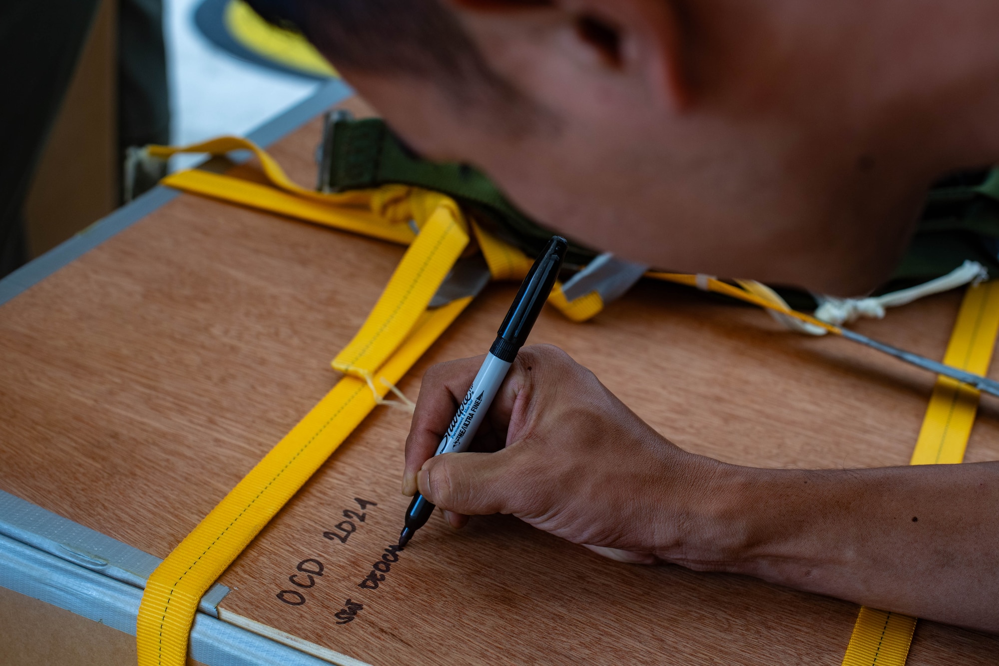 A man writes his name on a box.