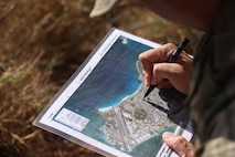 A U.S. Army forward observer with 25th Infantry Division marks a map of Marine Corps Base Hawaii during a simulated close air support exercise, MCBH, Nov. 20, 2024. 3d LCT fire support teams, joint terminal attack controllers, and forward air controllers executed dry close air support with civilian contracted fixed-wing aircraft and Boeing AH-64 Apaches in support of training and readiness standards for Marine Corps air controllers. The fire support teams, who worked in conjunction with Army forward observers from 25th Infantry Division, ran battle drills and addressed scenarios in order to refine joint and internal techniques and procedures for directing surface-to-surface and air-to-surface fires. (U.S. Marine Corps photo by Lance Cpl. Taylor Von Sanders-Frazer)