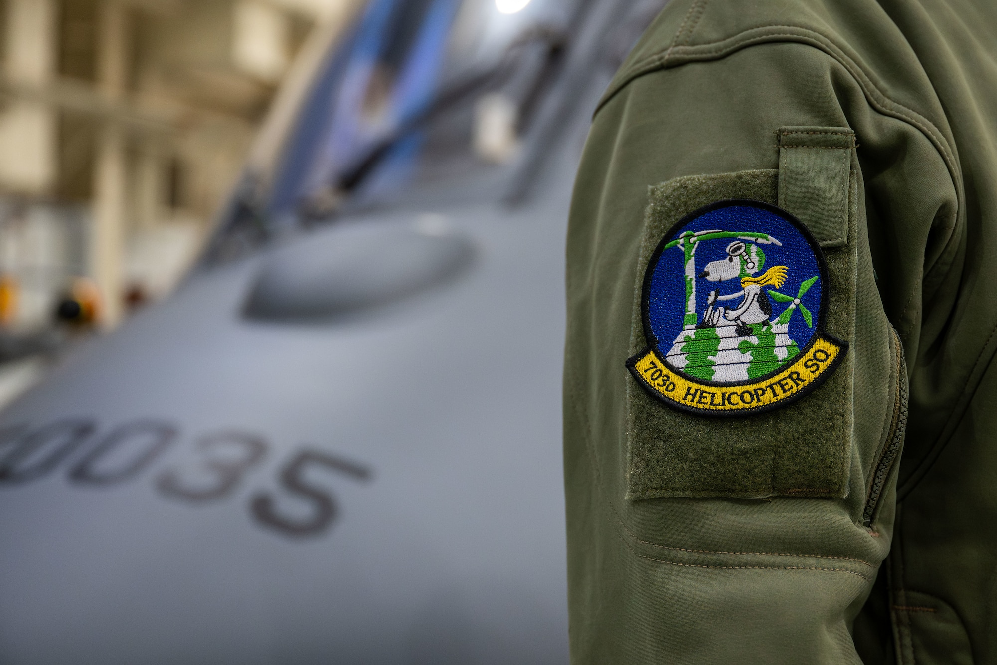 A member from the 703rd Helicopter Squadron displays the unit patch in front of an Integrated Aircrew Systems Trainer at Maxwell Air Force Base, Alabama on Dec. 11, 2024.