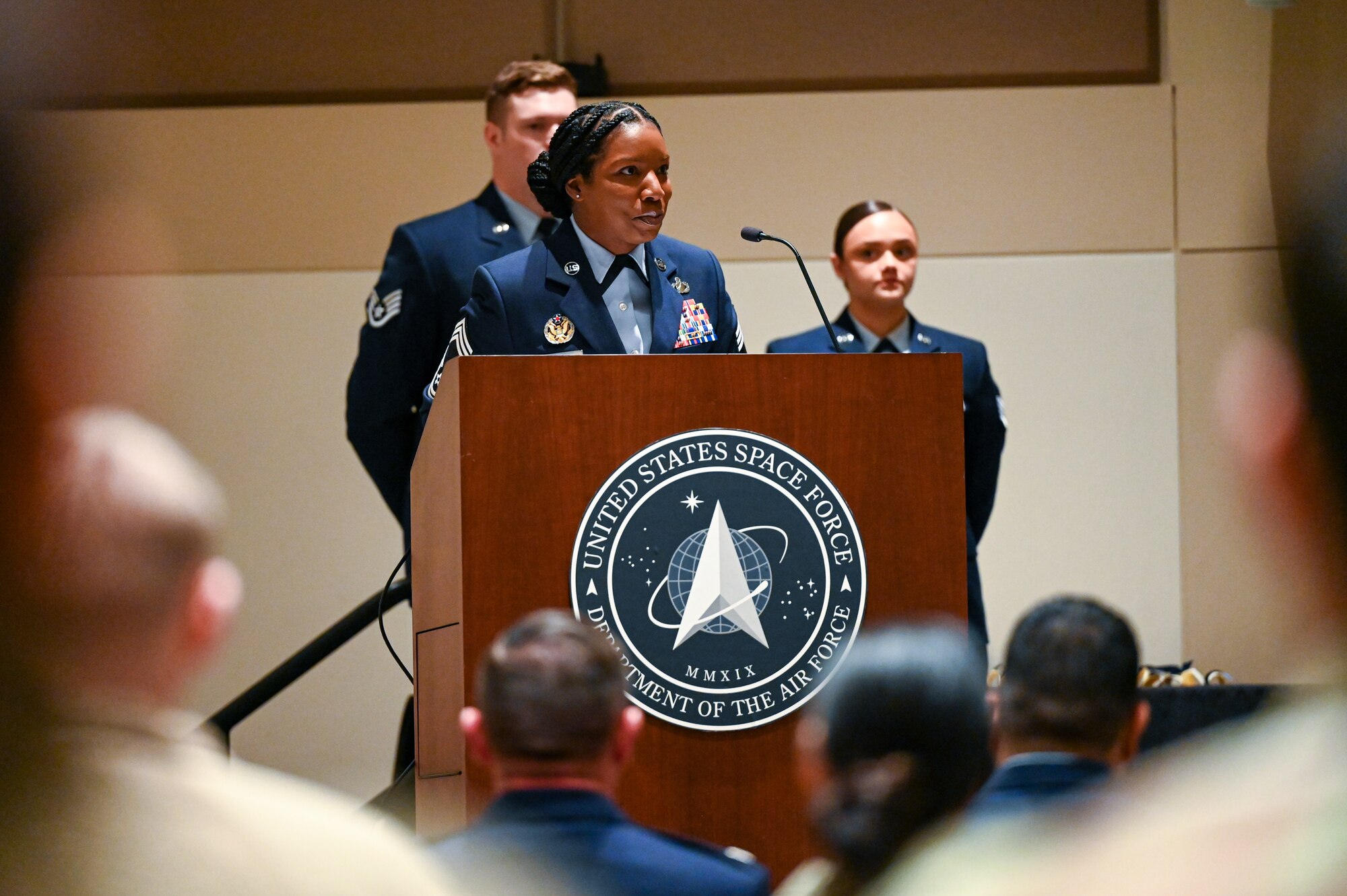 woman in air force uniform speaks to crowd at podium