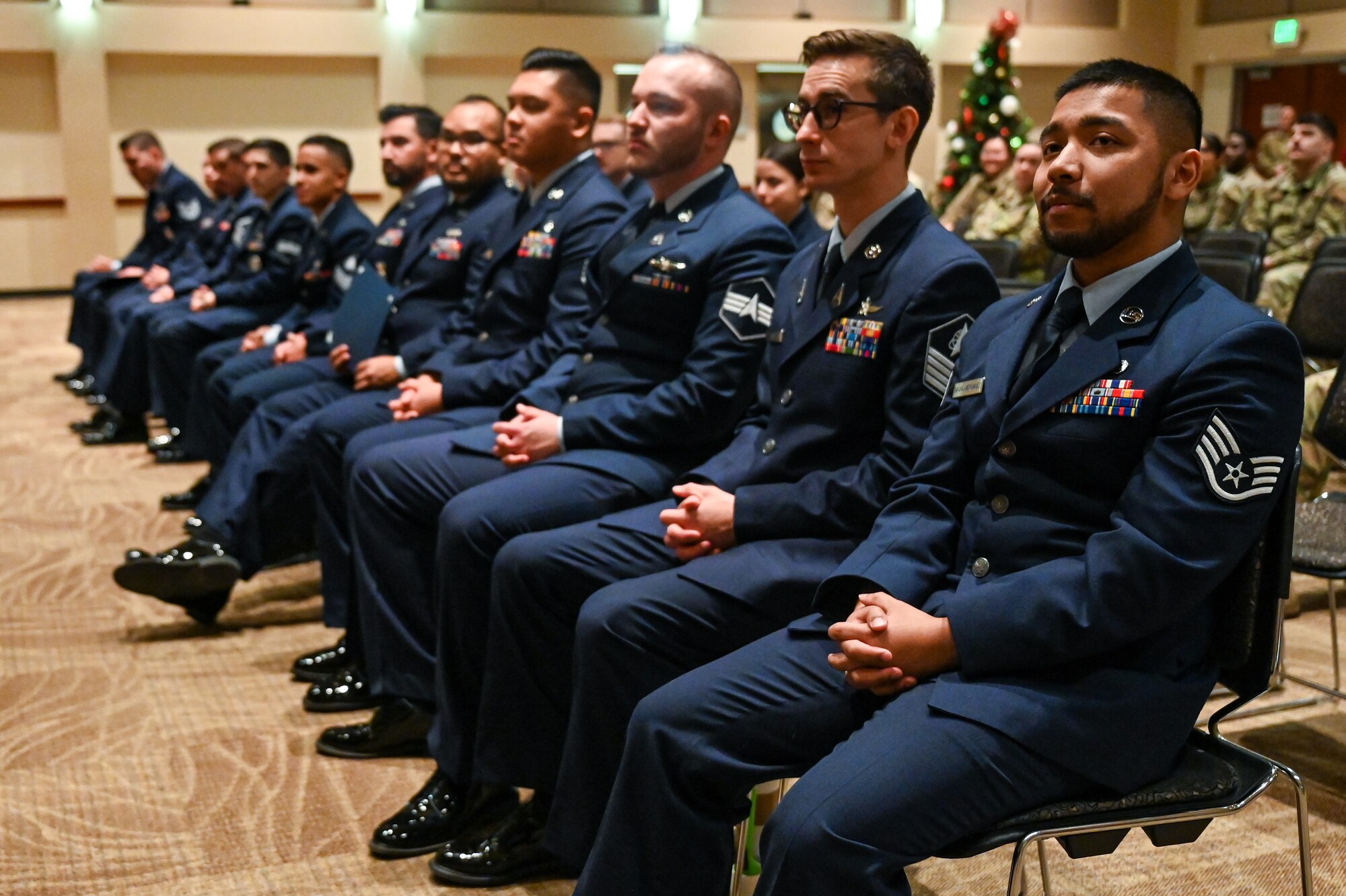 air force personnel sit and listen to speaker